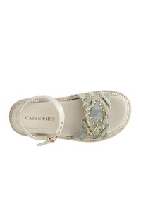 Vita läder sandal med vristrem och en denimtåband med fransiga kanter och gyllene nitar. Platt sula med texturerad yta.