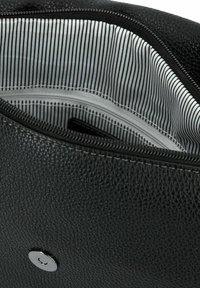 Interno di una borsa in pelle nera texture con chiusura a zip; presenta una fodera in tessuto rigato bianco e nero e una tasca interna.