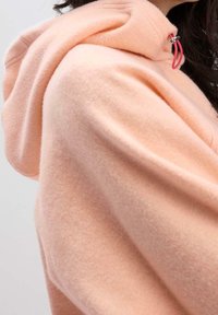 Felpa con cappuccio rosa chiaro realizzata in morbido tessuto in pile, con chiusura a coulisse con dettaglio rosso e vestibilità comoda e rilassata.