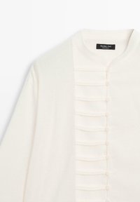 Witte cardigan met een textuur op het voorpaneel, voorzien van een rij van zeven met stof bedekte knopen en een ronde halslijn.