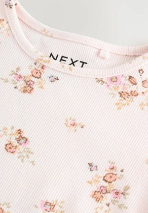 Tissu côtelé rose clair avec un motif floral dans des tons de rose et de marron, doté d'un col arrondi et d'une étiquette portant la mention "NEXT".