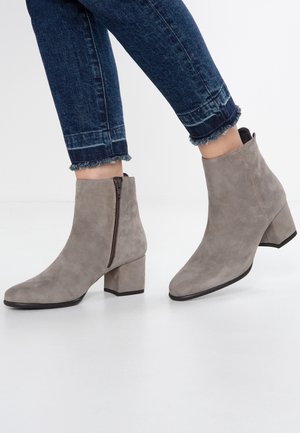 Grå ruskinds ankelstøvler med firkantet tå, slank blokhæl og sidelukning med lynlås. Båret med mørke denim jeans med frynsede kanter.