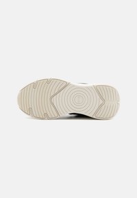 Sola de sapato feita de um material de borracha creme, texturizada com linhas circulares e paralelas para melhor aderência, com bico arredondado e um pequeno salto.
