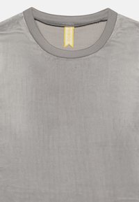 Weiches graues Samt-Rundhalsshirt mit geripptem Kragen und kleinem gelbem Markenzeichen innen am Ausschnitt.