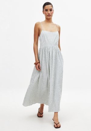 Striped maxi dress with thin straps, cinched waist, and flowing skirt. Colors include light blue and white, featuring vertical stripes.