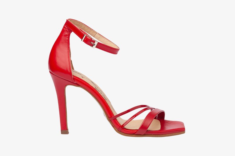 Sandal de tacón alto rojo con cuero sintético brillante, tres tiras finas y un hebilla en el tobillo. Punta abierta y un tacón delgado y afilado.