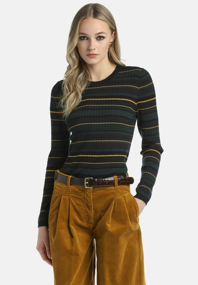 Maglione a maniche lunghe a coste di colore verde scuro con sottili strisce gialle e olive. Abbinato a pantaloni in corduroy a vita alta di colore senape.