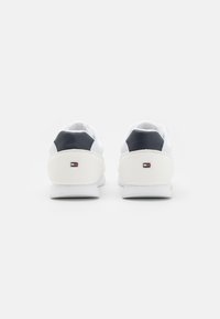 Białe sneakersy z granatowym akcentem na pięcie i detalem logo. Siatkowe i gładkie materiały z zaokrąglonym czubkiem oraz amortyzowaną podeszwą.