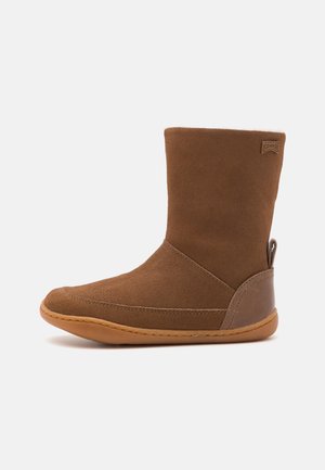 Stivaletto in suede marrone con punta arroton data, suola in gomma e dettagli cuciti; presenta una linguetta sul retro per un facile indossamento.
