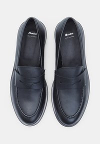 Mocasini din piele neagră cu talpă plată, detalii cusute și o bandă decorativă în partea din față. În interior se află brandul "Bata Real Leather".