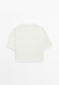 Bílý krátký crop tričko vyrobené z měkké tkaniny, s krátkými rukávy a uvolněným střihem. Jednoduchý design bez viditelných vzorů nebo akcentů.