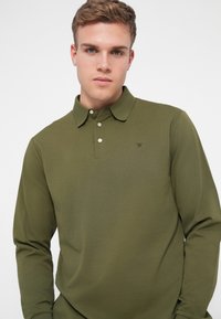Oliwkowa, długorękawowa koszulka polo z bawełny, z kołnierzykiem, trzema guzikami z przodu i małym logo na lewej piersi.