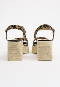 Sandalias de plataforma con estampado de leopardo, con un tacón tejido beige texturizado y una correa en el tobillo, que presentan un cierre de hebilla y un forro interior suave.
