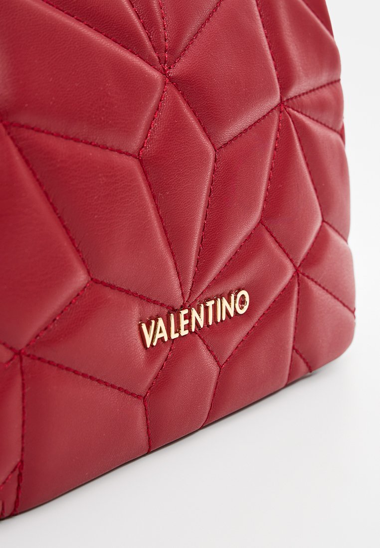 Bolso de mano de cuero acolchado rojo con patrón de diamante y logotipo dorado de "VALENTINO". Textura suave con apariencia acolchada y bordes redondeados.
