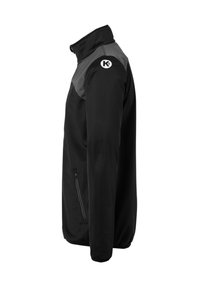 Zwarte en grijze jas met ritszak aan de zijkant en een witte ronde logo met een "K" op de bovenste linker mouw, gezien vanaf de zijkant.