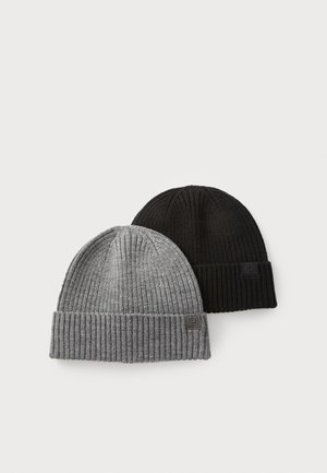 Due berretti di lana, uno grigio e uno nero, con texture a coste e risvolti. Ognuno include un piccolo patch con logo.