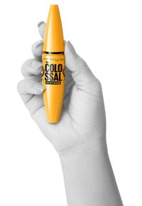 Tube de mascara jaune avec des accents noirs, présentant un design effilé. L'étiquette indique "le COLOSSAL" et "NOIR FUMÉ". Tenue dans une main.