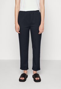 Marinblå tapered byxor med elastiskt midjeband, som har sidofickor, manschetter och en mjuk tygtextur.