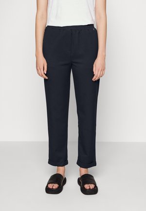 Marinblå tapered byxor med elastiskt midjeband, som har sidofickor, manschetter och en mjuk tygtextur.