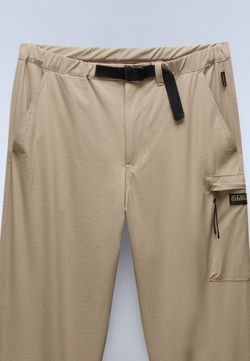 Pantalones de senderismo beige con una amplia cinturilla elástica y un cinturón negro ajustable. Incluyen un bolsillo lateral con cierre de cremallera. Textura suave.