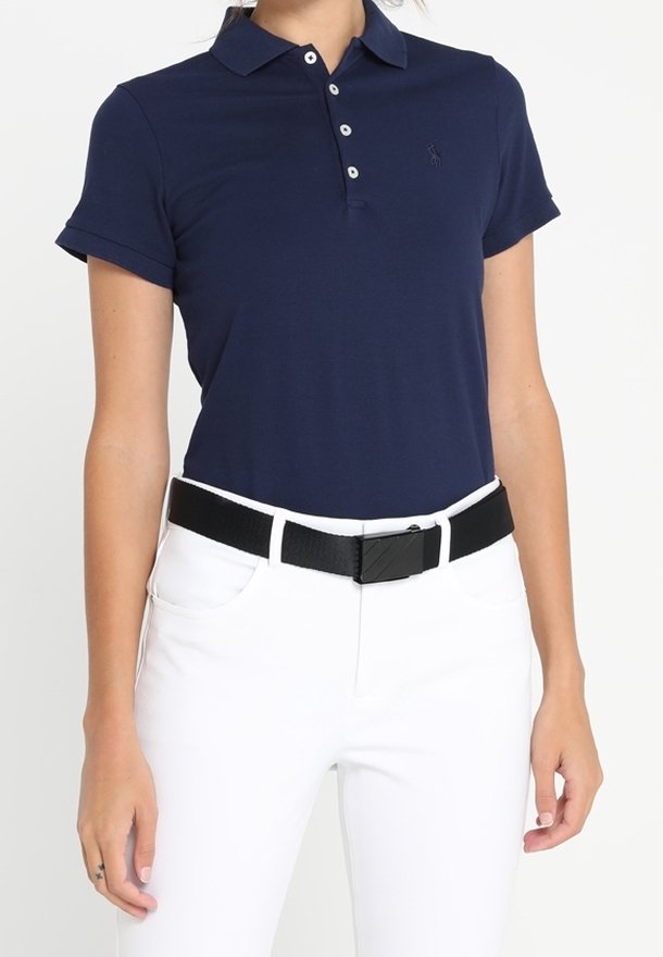 Mörkblå pikétröja med korta ärmar, ribbad krage, placket med tre knappar och en broderad logotyp, kombinerad med vita byxor och ett svart bälte.