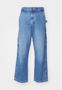 Light blue denim cargo pants with a relaxed fit, multiple side pockets, and a wide leg design. Features a button and zipper closure.