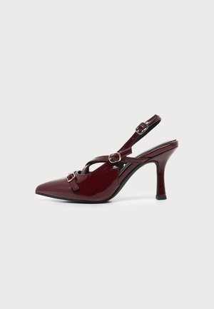 Γυναικείο παπούτσι slingback με ψηλό τακούνι από μπορντό πατεντέ δέρμα, μυτερή μύτη και τρεις χρυσές αγκράφες, σε λευκό φόντο.