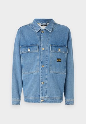 Blaue Jeans-Knopfjacke mit langen Ärmeln, zwei vorderen Klappentaschen und einem kleinen schwarz-gelben Markenpatch auf der rechten Tasche.