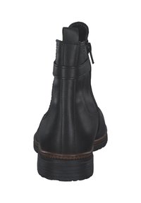 Bottines en cuir noir avec fermeture éclair, dotées d'une semelle texturée marron, d'une finition lisse et d'un détail de sangle simple en haut.