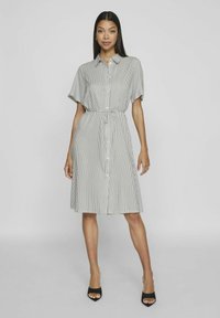 Pruhovaná šatová sukně z lehkého materiálu s límečkem, krátkým rukávem, páskem na zavázání v pase a délkou ke kolenům.