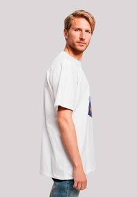 Weißes Baumwoll-T-Shirt mit lockerem Schnitt und kurzen Ärmeln, mit einem bunten Grafikdesign auf der Vorderseite. Klassischer Rundhalsausschnitt.