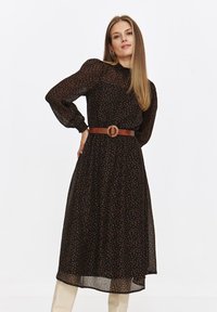 Czarna sukienka z długim rękawem, z kolorowym wzorem kropek, zwężona w talii brązowym paskiem z okrągłą klamrą. Lekka, zwiewna tkanina.