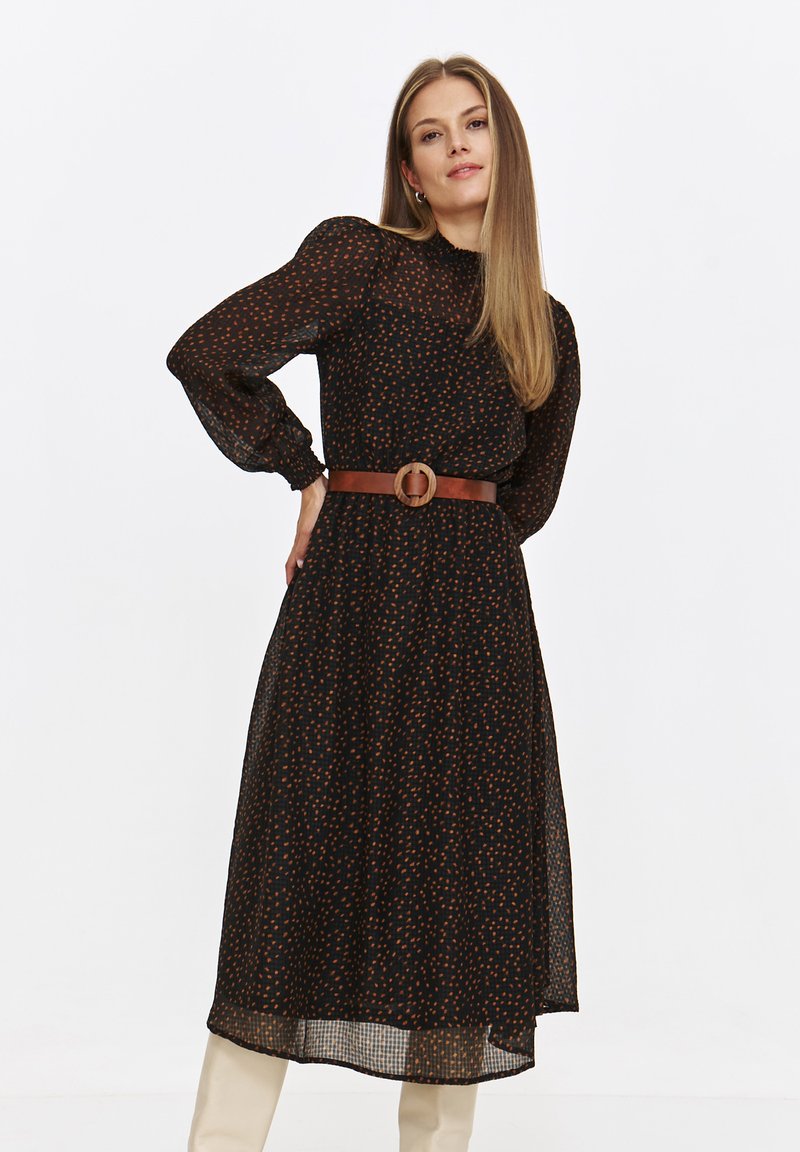 Czarna sukienka z długim rękawem, z kolorowym wzorem kropek, zwężona w talii brązowym paskiem z okrągłą klamrą. Lekka, zwiewna tkanina.