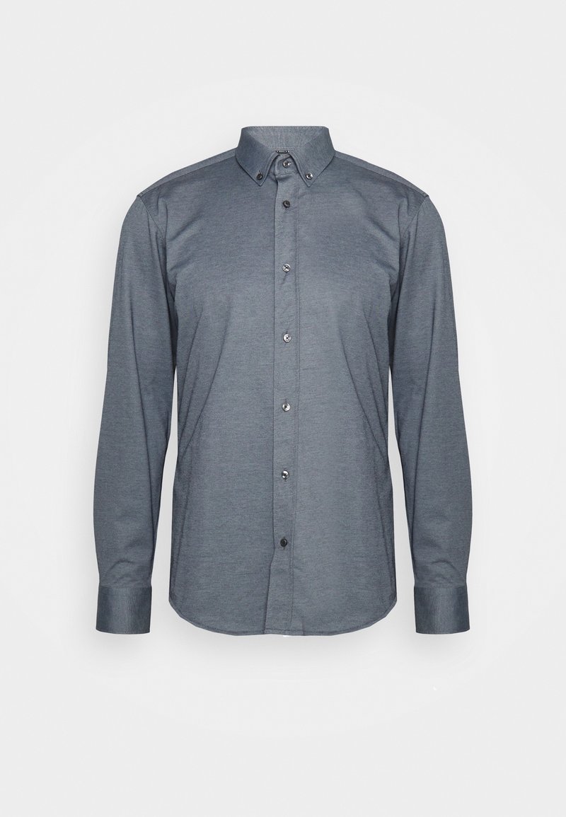Chemise habillée gris foncé à manches longues, boutonnée, col boutonné, sur fond uni clair.
