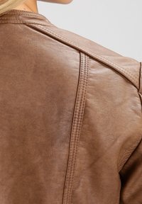 Bruine leren jas met een gladde textuur, gestikte details op de schouders en rug, en een getailleerd ontwerp.