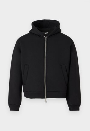 Svart zip-up hoodie tillverkad av mjukt material. Har en fodrad huva, sidofickor och ribbade ärmslut. Enkel design med sömlöst utseende.