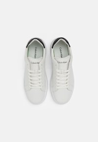 Sneaker bianche in pelle con finitura liscia, punta tonda e chiusura con lacci a sei fori. Tallone posteriore nero a contrasto, interno verde e branding visibile.