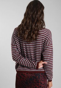Maglione a righe in grigio e bordeaux. Vestibilità comoda con maniche lunghe e orlo a coste, abbinato a una gonna con stampa leopardata. Tessuto morbido.
