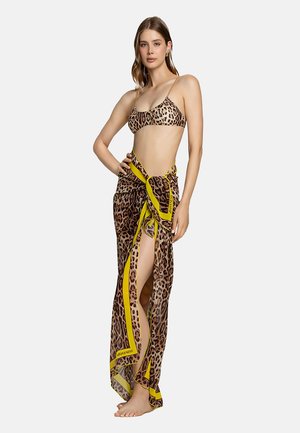 Bikini de estampado de leopardo con una falda envolvente translúcida que presenta un ribete de acento amarillo. Tejido ligero, diseño fluido, alto abertura en un lado.