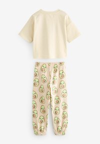 Beige pamut cropped top rövid ujjakkal, bézs joggingnadrággal párosítva, amely avokádó mintával van díszítve, rugalmas bokákkal.