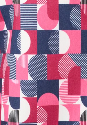 Tejido multicolor con patrón geométrico, que presenta formas en rosa, azul marino y blanco, incluyendo círculos y cuadrados con rayas y rellenos sólidos.