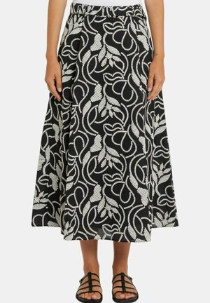 Gonna midi a motivi in bianco e nero con design astratto di foglie, indossata con sandali neri con cinturini.