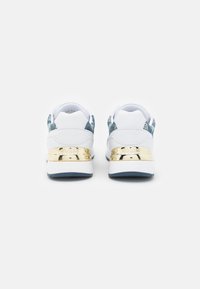 Zapatillas blancas con un diseño estampado azul en la parte trasera, con un acento metálico dorado en el tal�ón y un diseño texturizado. Suela de goma, estilo de cordones.
