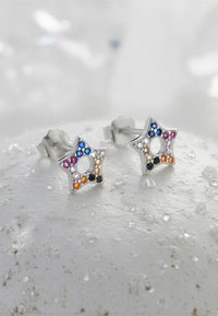 Silverstjärnformade örhängen med färgglada ädelstenar i blått, rosa, orange, svart och klart. Texturerad yta med ett utskuret centrum.