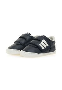 Zapatos de cuero negros con acentos blancos, forma de punta redonda, dos correas de Velcro y una suela texturizada, con un detalle de logo en el costado.