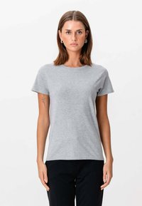 Grå bomulds t-shirt med korte ærmer og rund hals. Blød tekstur og en tætsiddende silhuet, parret med sorte bukser.