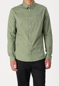 Camicia verde a maniche lunghe realizzata in cotone, con colletto classico e un piccolo logo sul petto, completata da bottoni bianchi.