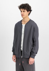 Grå bomberjacka med dragkedja framtill, ribbade ärmslut och sidofickor. Tillverkad av mjukt tyg har den en avslappnad passform och en minimalistisk design.