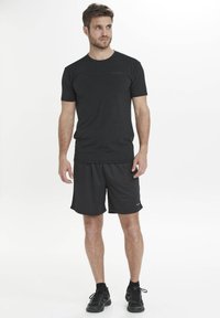 Svart atletiskt t-shirt och shorts i lätt material, med rundad halslinning och logodetalj. Bärs med svarta sneakers.