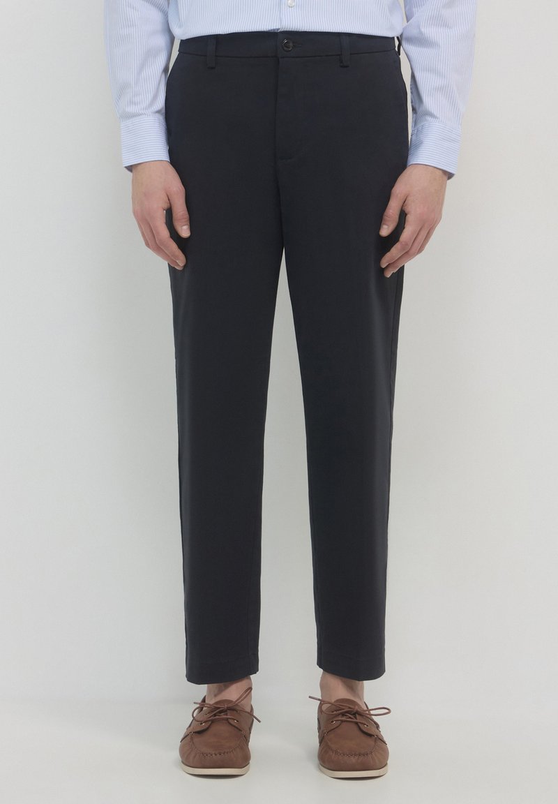 Marineblaue Hose mit geradem Bein, hergestellt aus einem glatten Stoff. Mit Knopfverschluss, Gürtelschlaufen und Seitentaschen.